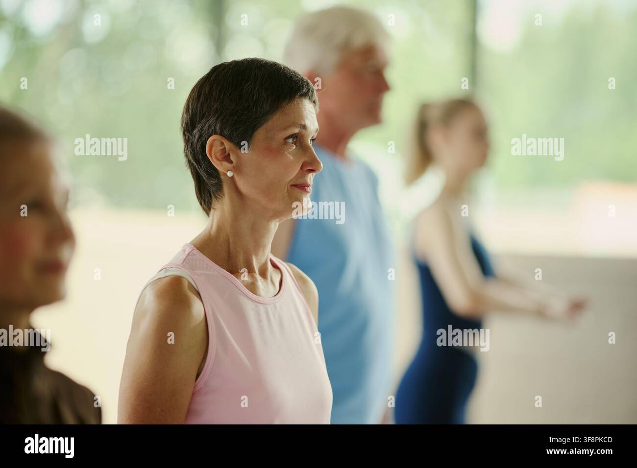 Femme caucasienne mûre participant à un cours de fitness en groupe avec un homme senior et une jeune femme, promouvant un mode de vie actif et le bien-être, plan moyen Banque D'Images