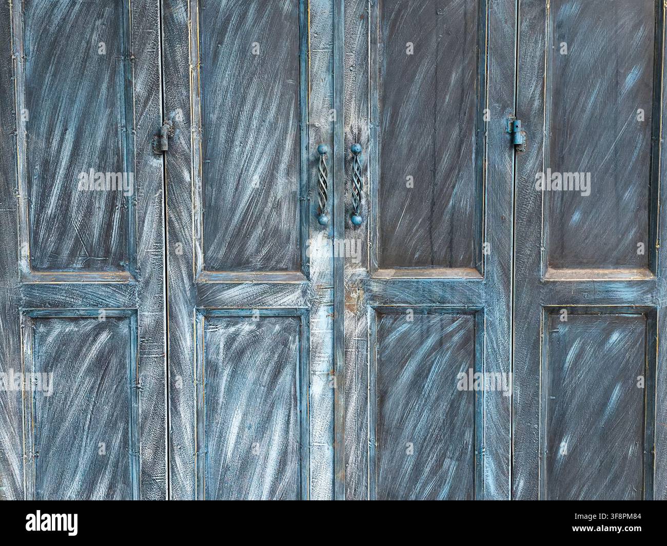 Une porte en bois bleu patinée avec des coups de peinture texturés et des poignées en métal rustiques évoquant un charme vieilli et une atmosphère calme Banque D'Images