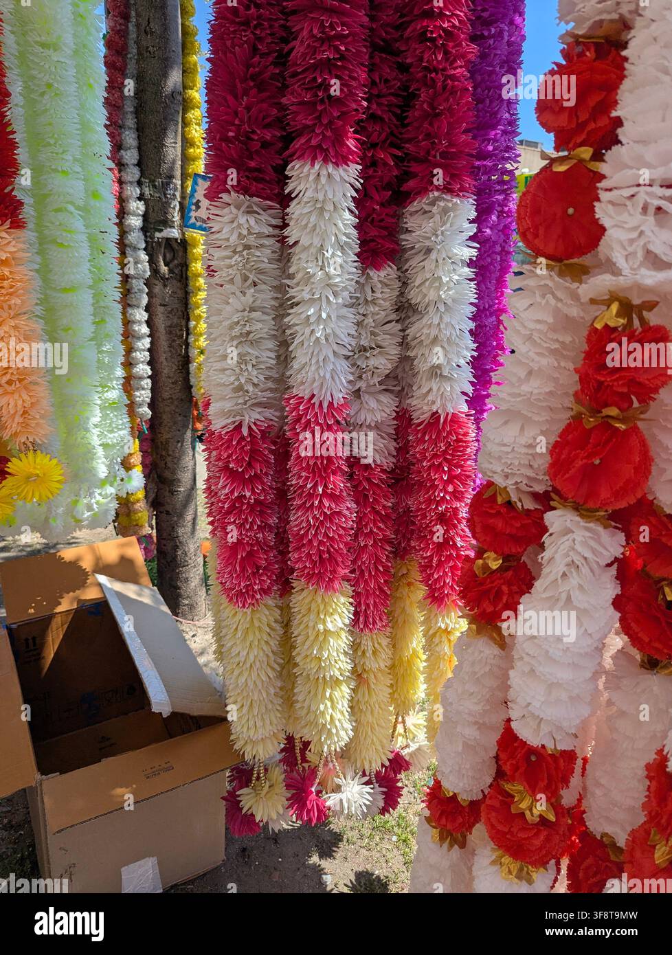 Guirlandes de fleurs artificielles utilisées comme décoration pour les fêtes hindoues, souvent arborant des couleurs vives – rouge, jaune et blanc – dans la Liberty Avenue, NY. - Image de stock capturée avec un smartphone
