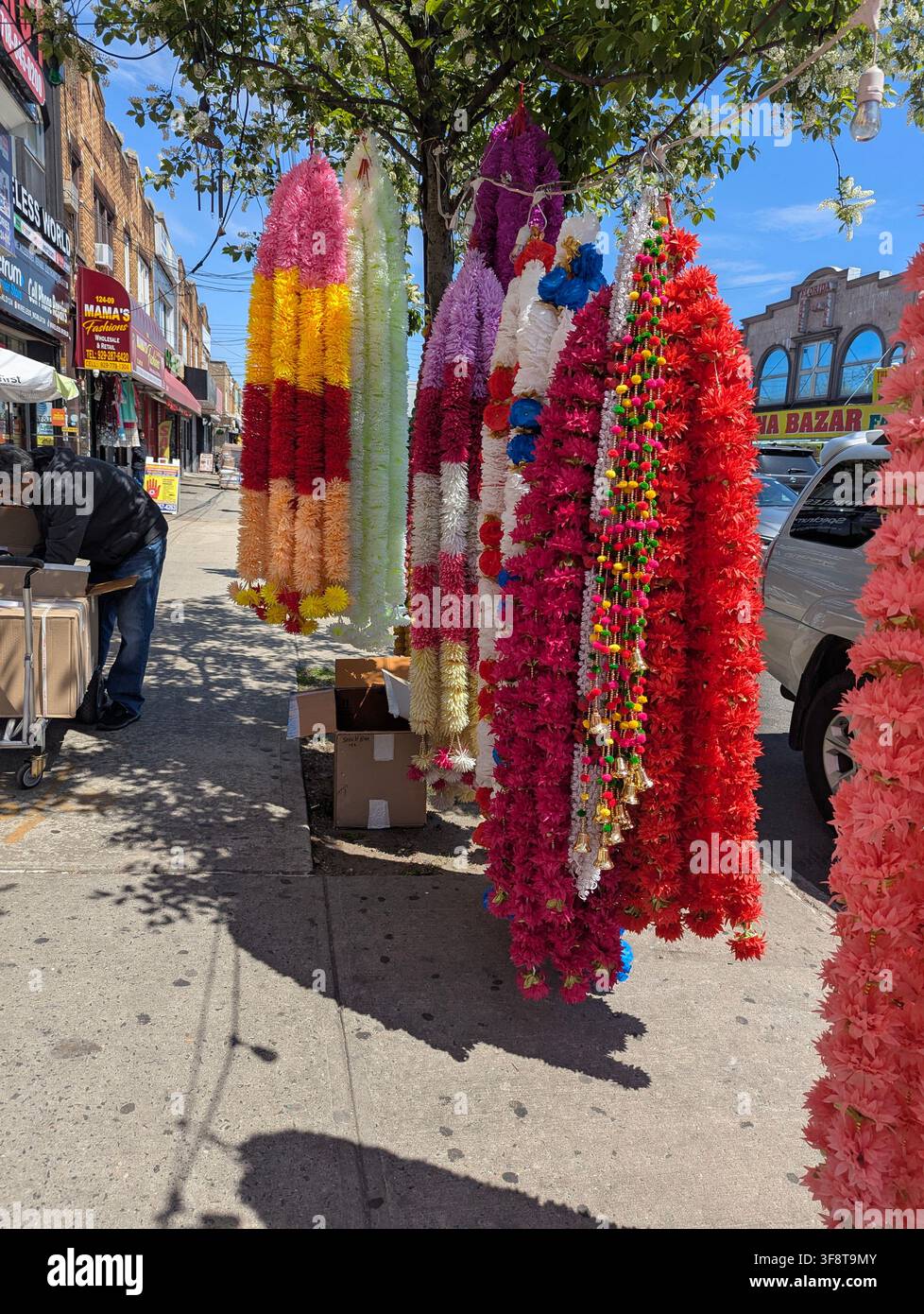 Guirlandes de fleurs artificielles utilisées comme décoration pour les fêtes hindoues, souvent arborant des couleurs vives – rouge, jaune et blanc – dans la Liberty Avenue, NY. - Image de stock capturée avec un smartphone