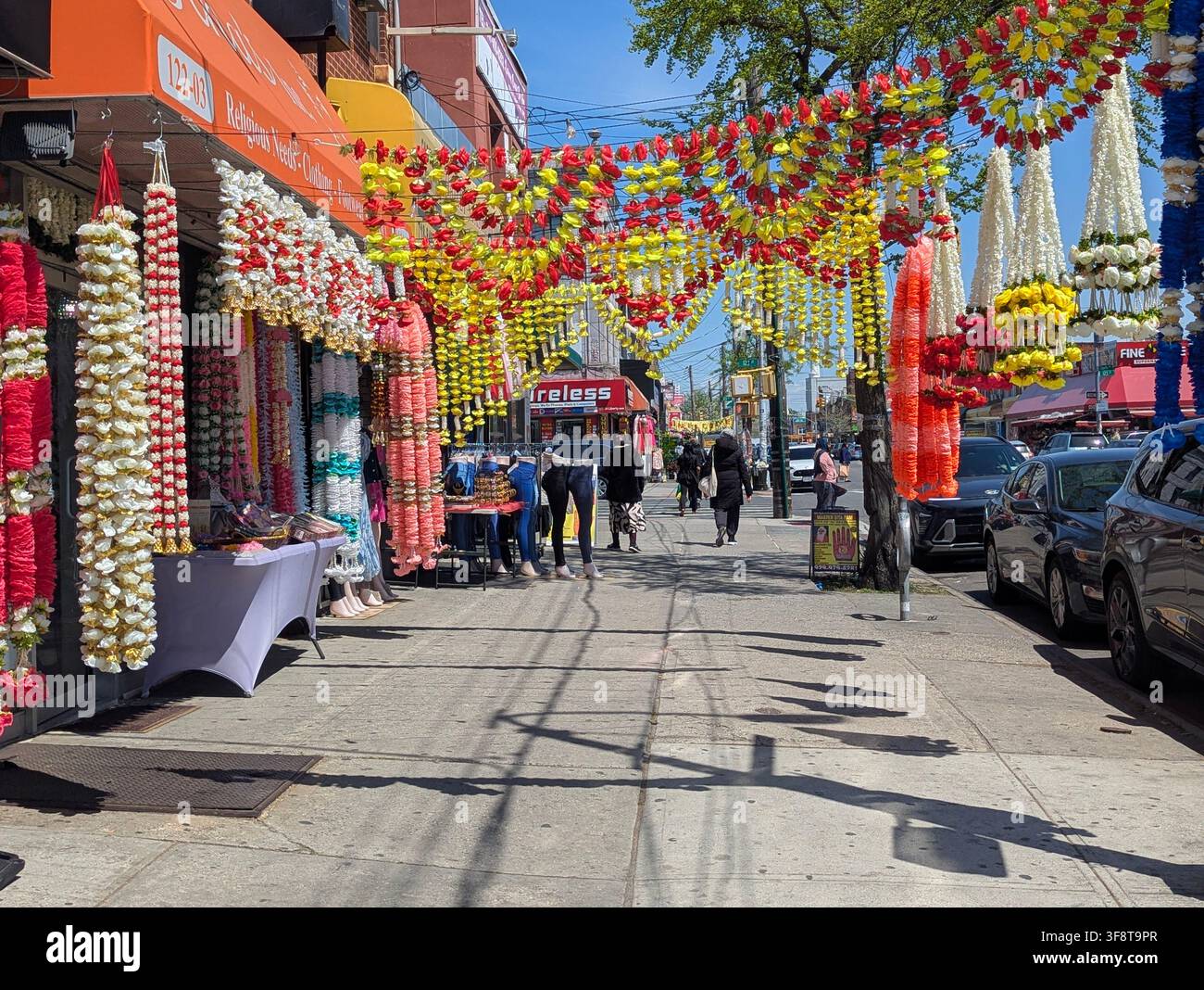 Guirlandes de fleurs artificielles utilisées comme décoration pour les fêtes hindoues, souvent arborant des couleurs vives – rouge, jaune et blanc – dans la Liberty Avenue, NY. - Image de stock capturée avec un smartphone