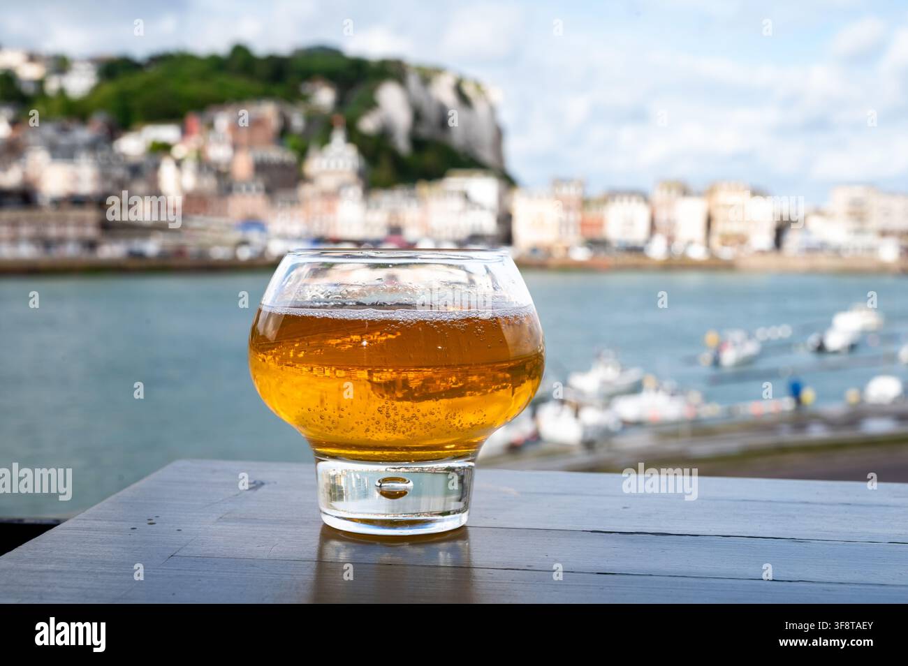 Cidre de pomme de Normandie versé avec vue sur le Tréport avec de superbes falaises de craie dorées, boisson pétillante aux pommes, goût rafraîchissant. Sur fond pictu Banque D'Images