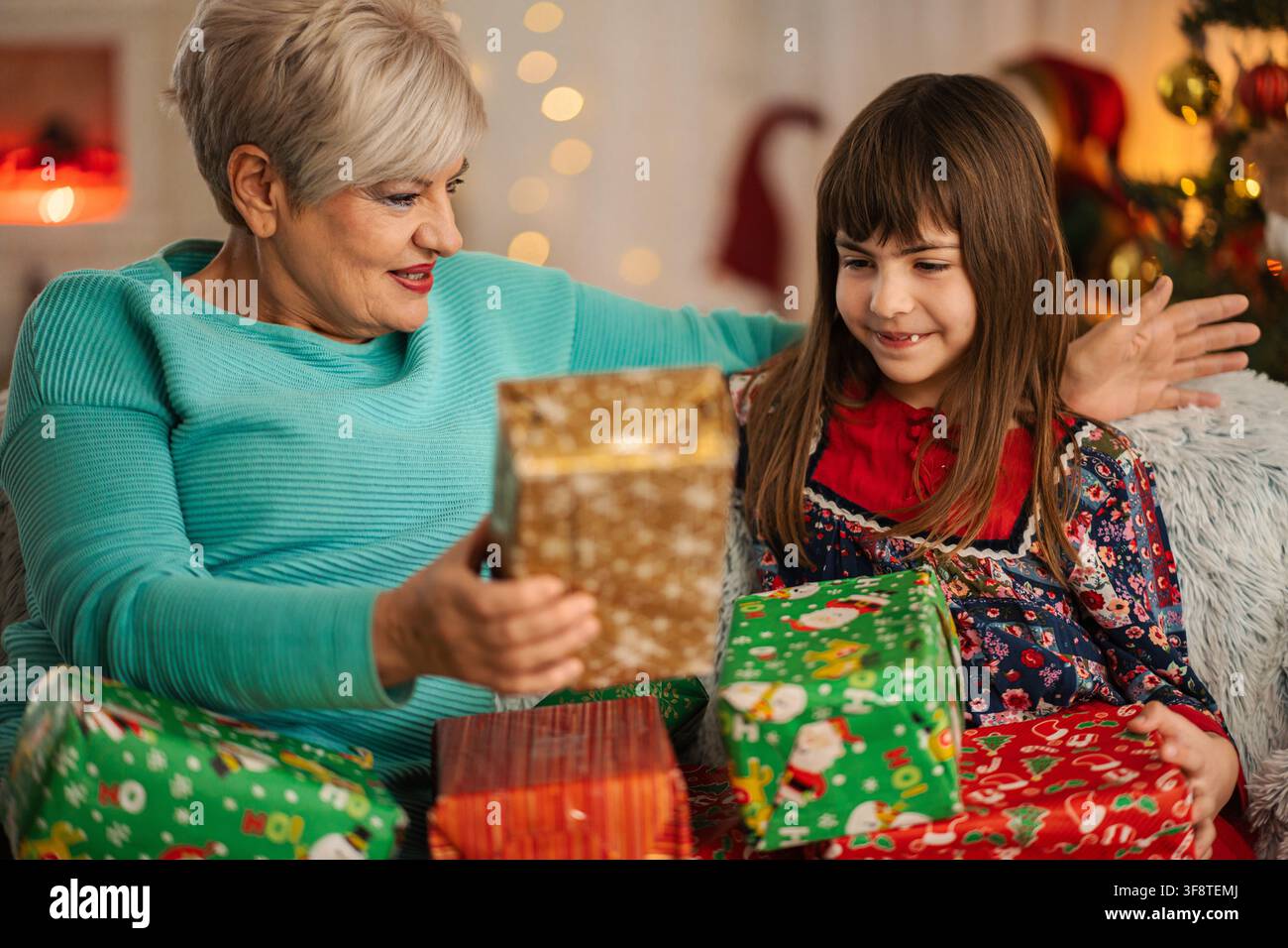 Grand-mère offrant un cadeau de Noël emballé à sa petite-fille heureuse Banque D'Images