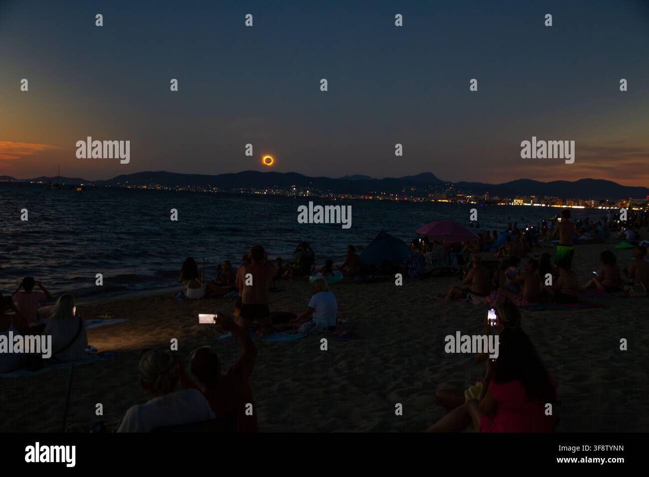 L'éclipse solaire totale brille au-dessus des eaux assombries au large de Majorque le 12 août 2026, les spectateurs regardent depuis la plage sous un crépuscule bleu profond Banque D'Images
