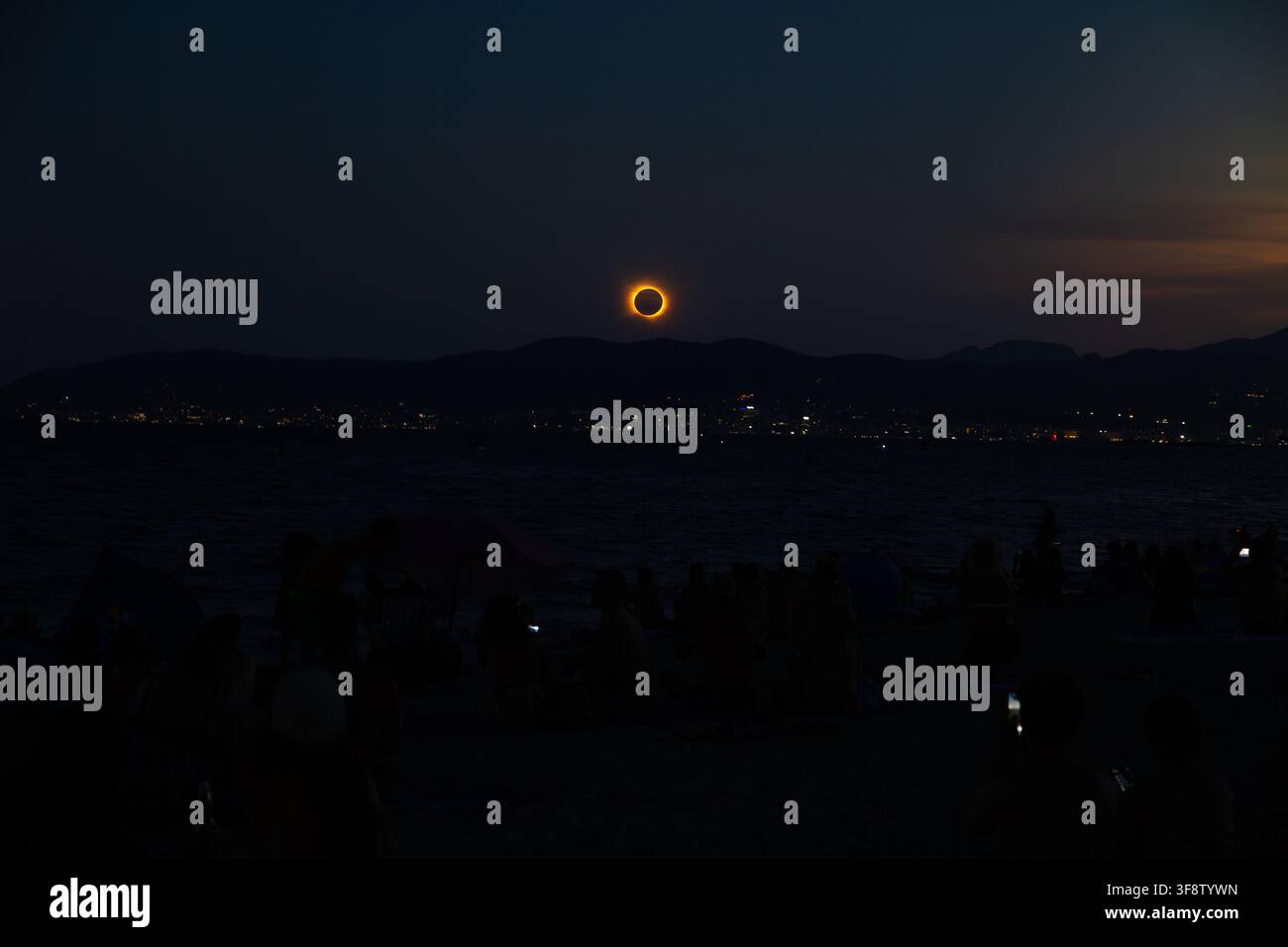 L'éclipse solaire totale brille au-dessus des eaux assombries au large de Majorque le 12 août 2026, les spectateurs regardent depuis la plage sous un crépuscule bleu profond Banque D'Images