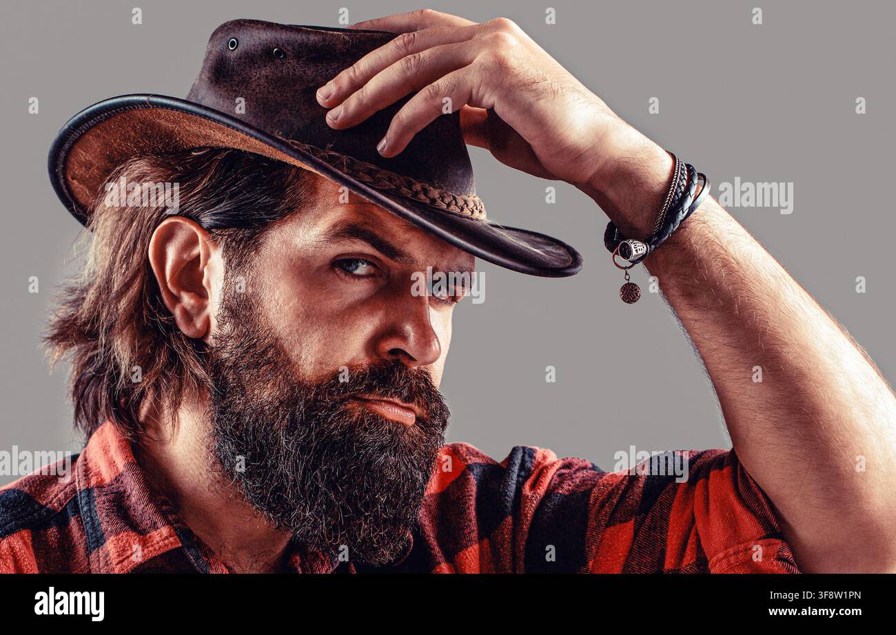 Cow-boy non rasé. Chapeau de cow-boy. Jeune homme séduisant ajustant son chapeau de cow-boy Banque D'Images