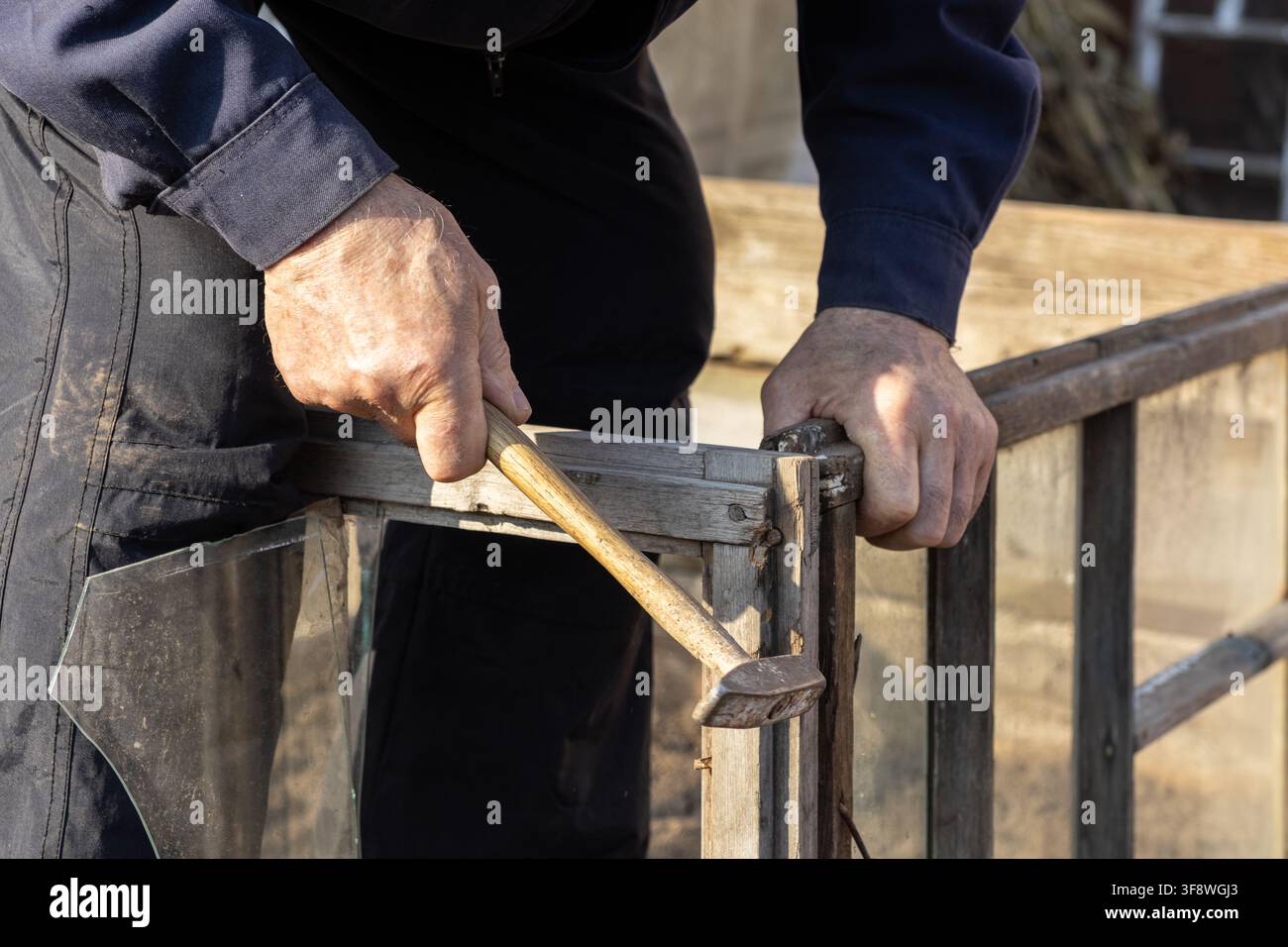 Un artisan travaille soigneusement avec un outil manuel sur une vitre usée, capturant l'essence du bricolage domestique, de la rénovation de bâtiments et du Banque D'Images