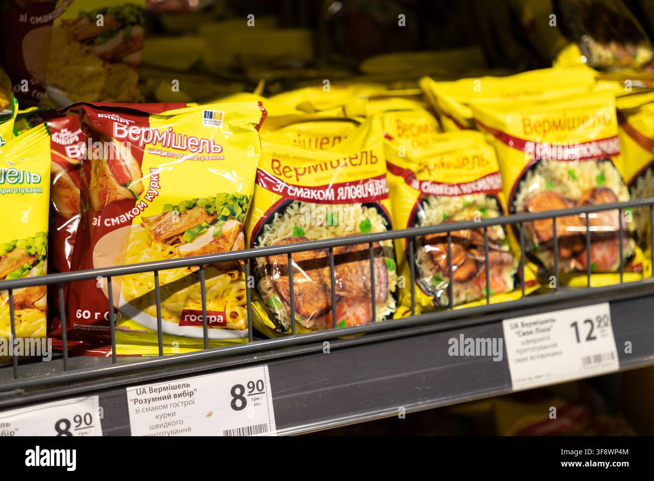 Horodok, Ukraine - 23 mars 2026 : Rangées de paquets de nouilles instantanées jaunes posés sur une étagère de supermarché, mettant en avant des produits de restauration rapide pratiques pour un accès facile Banque D'Images