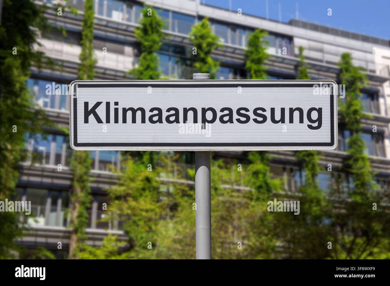 (Photomontage) Panneau portant l'inscription KLIMAANPASSUNG (adaptation au climat) devant un bâtiment à façade verte Banque D'Images