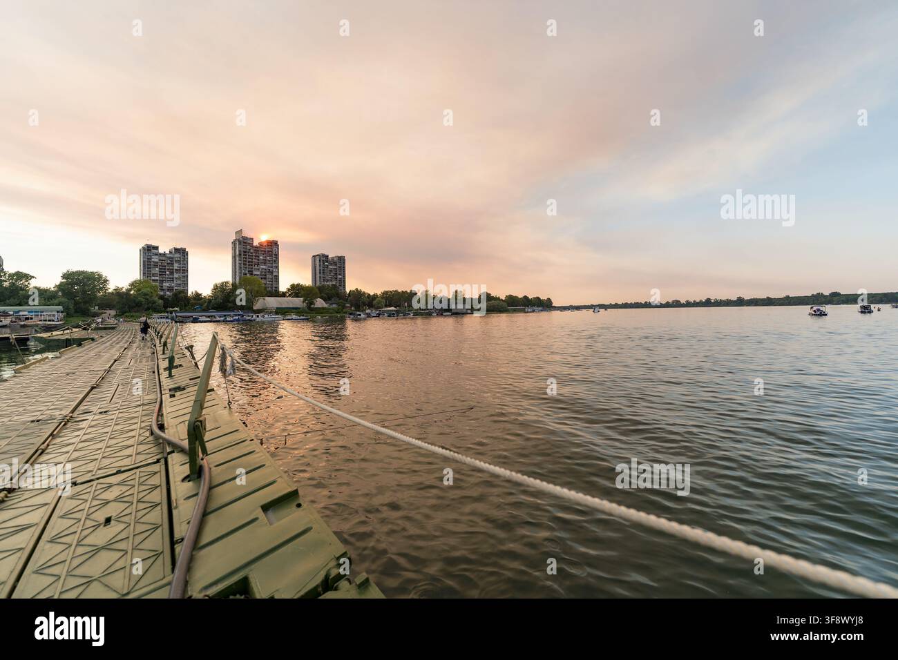 Une vue ultra grand angle d'un ponton métallique vert s'étendant sur le Danube à Belgrade, en Serbie, lors d'un coucher de soleil chaud en été. Haut ris Banque D'Images