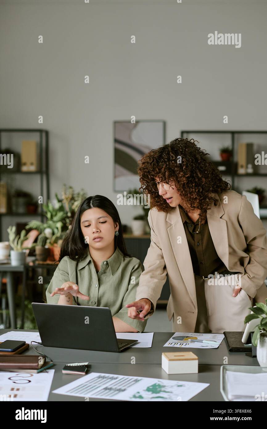 Différentes collègues féminines discutant un projet sur un ordinateur portable au bureau Banque D'Images