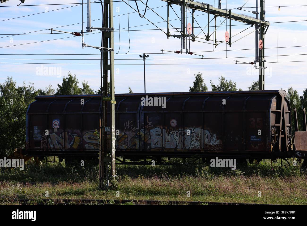 Wagon de train de marchandises couvert de graffitis, posé sur les voies ferrées à Östersund, en Suède, lors d'une soirée d'été. Banque D'Images
