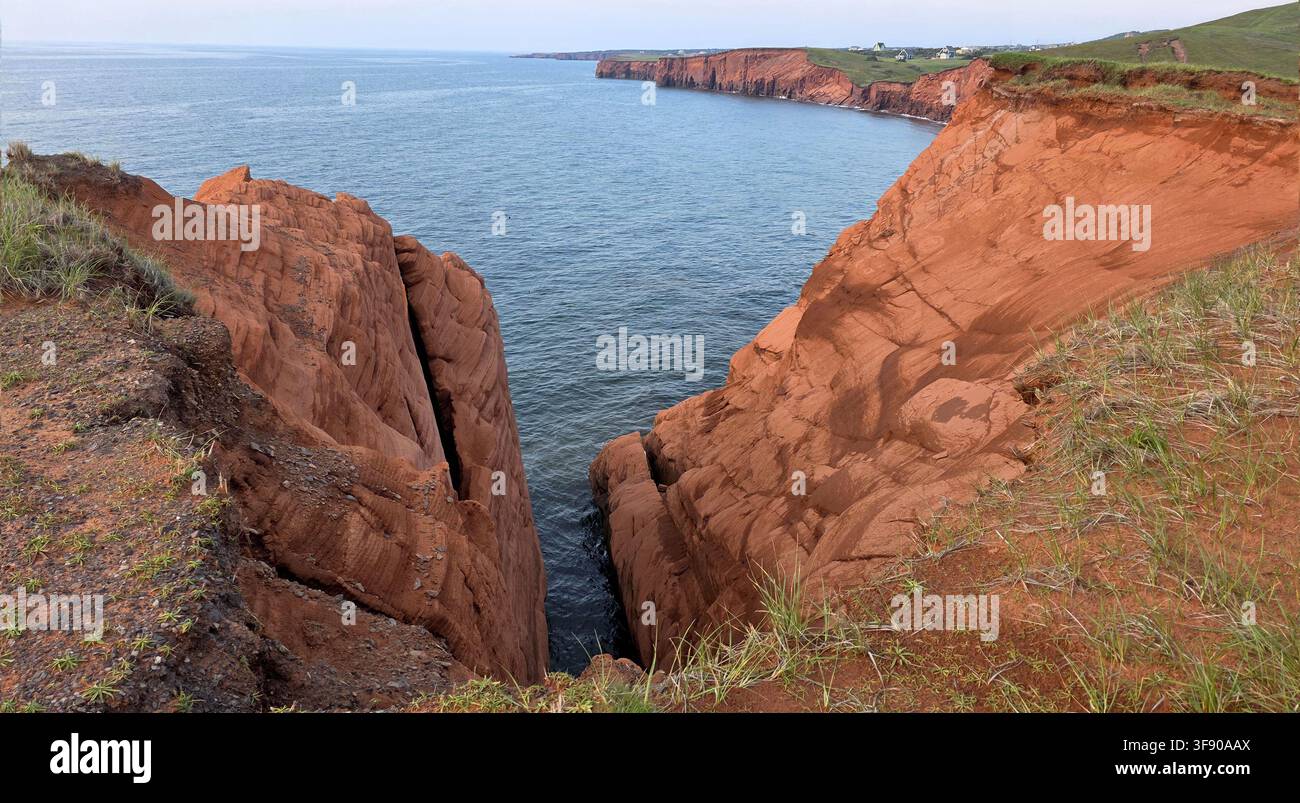 Falaises et formations rocheuses dramatiques en grès rouge s'étendant dans l'océan bleu aux Îles de la Madeleine, Québec, Canada. - Image de stock capturée avec un smartphone