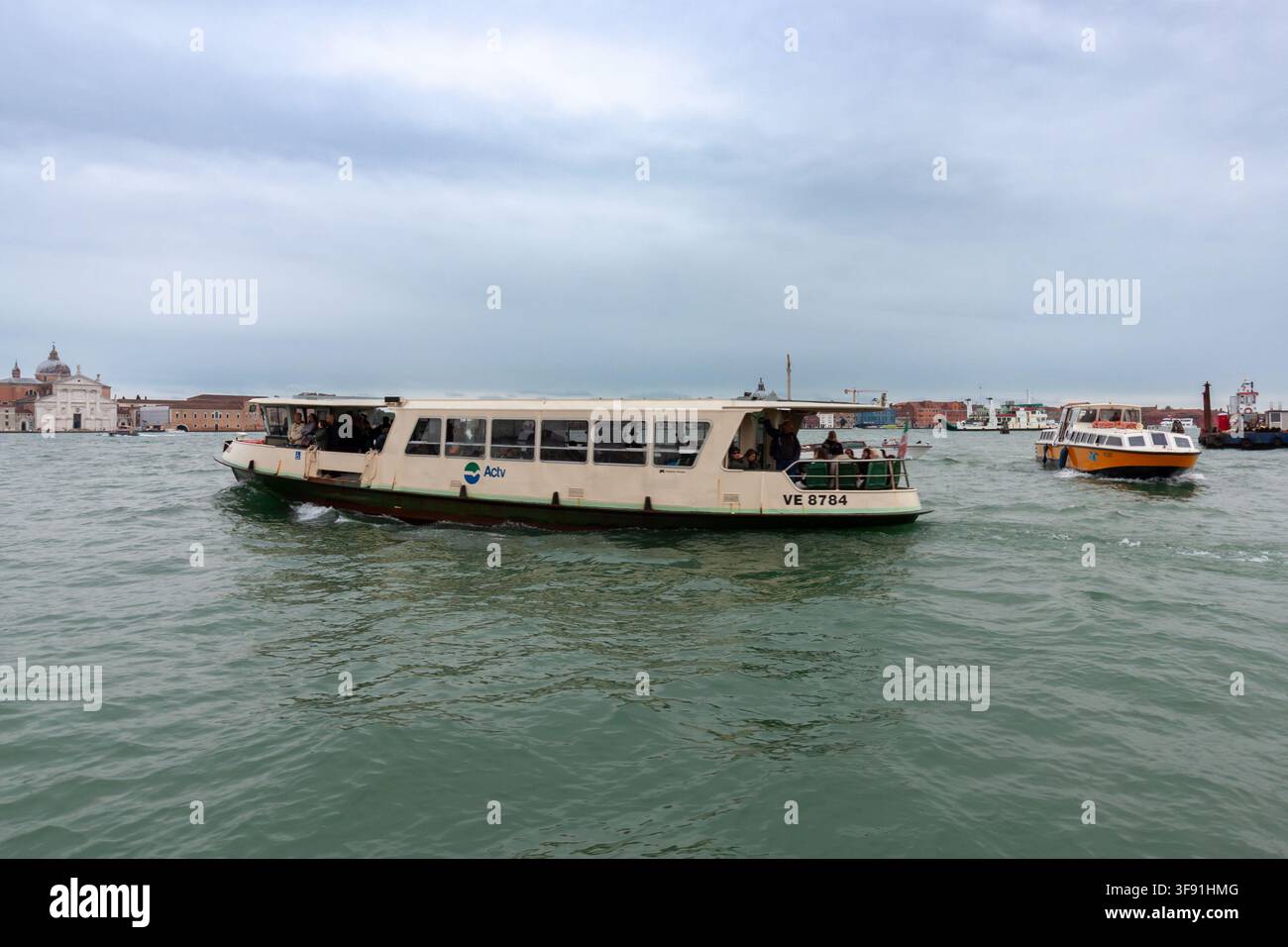VENISE, ITALIE - 24 OCTOBRE 2024 : Ferry public naviguant à travers une large voie d'eau urbaine sous un ciel nuageux dramatique Banque D'Images