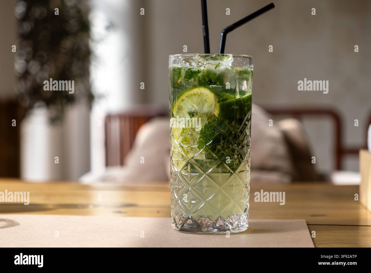 Le mojito refroidi dans un verre highball texturé contient de la glace, des agrumes et des herbes, créant une atmosphère invitante pour un repas social ou une célébration Banque D'Images