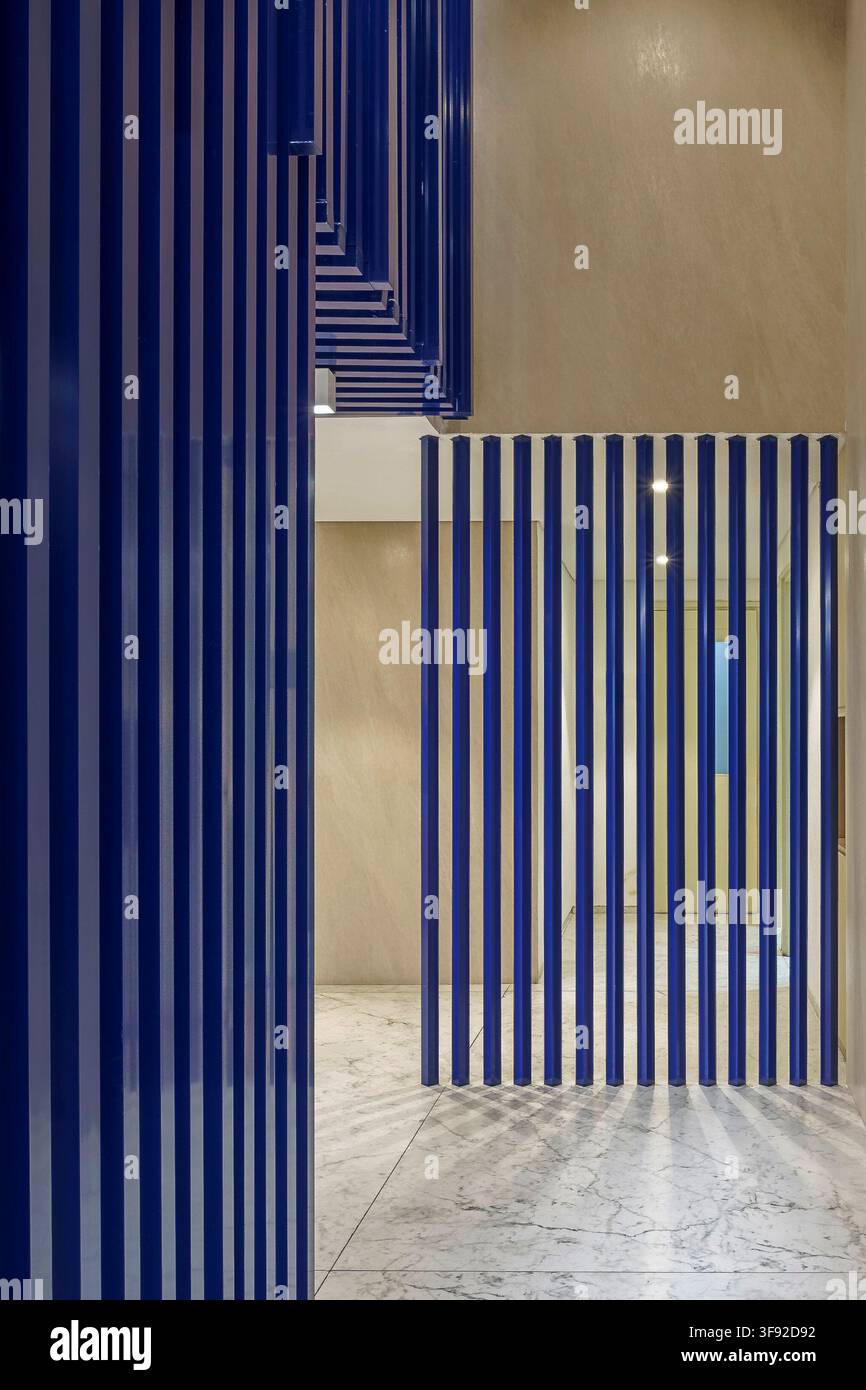 Perspective intérieure à faible angle montrant un écran métallique à lamelles bleu foncé frappant agissant comme un séparateur spatial élégant. Sur fond poli Banque D'Images