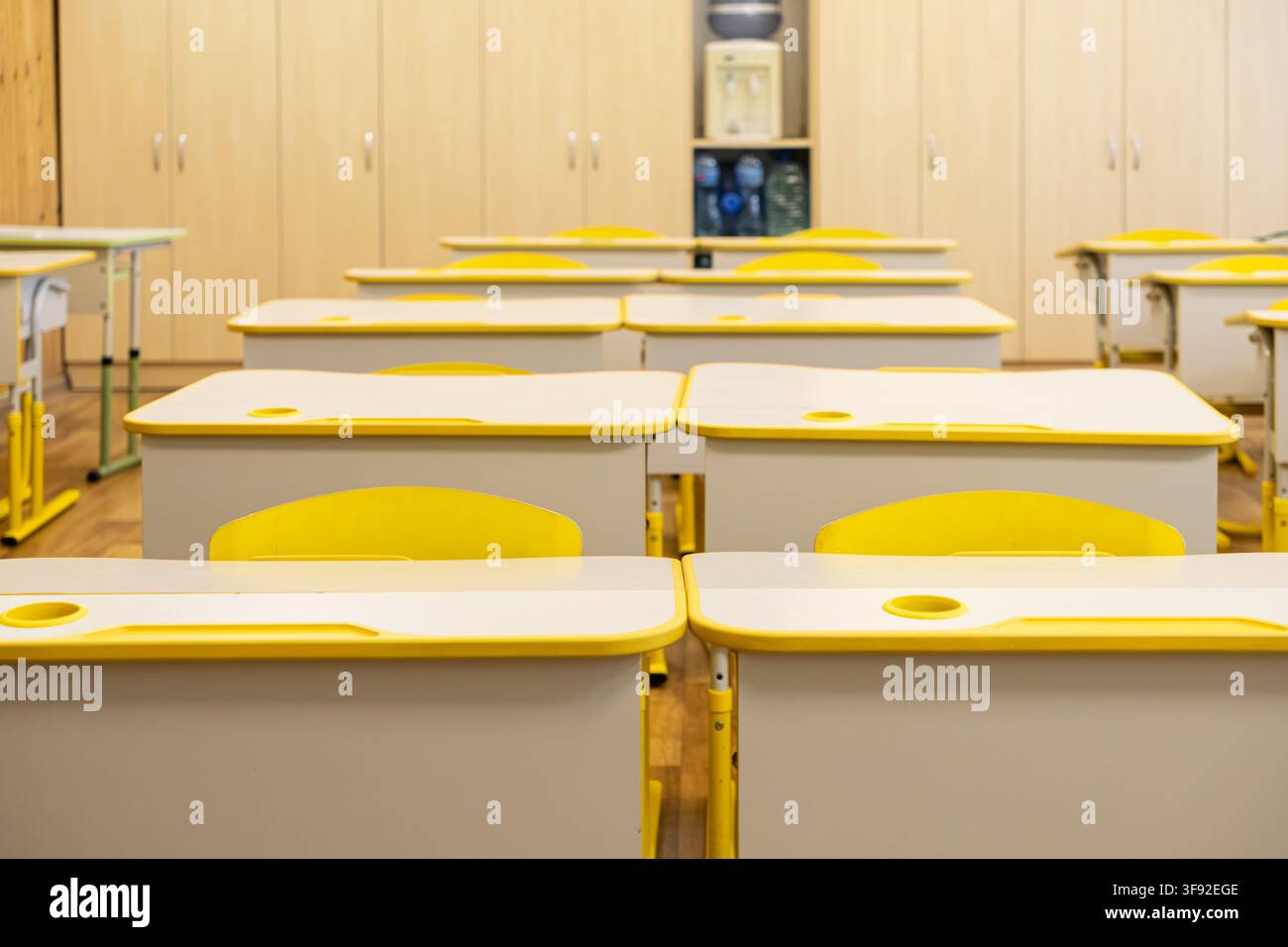 Des bureaux d'étudiants vides avec des accents jaunes sont alignés dans une salle d'école primaire pour offrir une atmosphère propre et invitante pour les activités d'apprentissage dans un Banque D'Images