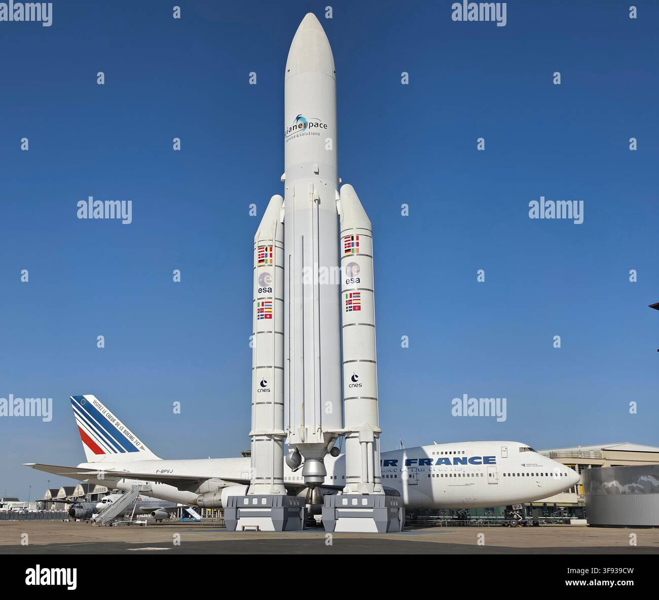 Modèle grandeur nature du véhicule de lancement spatial Ariane 5 debout à l'extérieur à côté d'un avion de ligne Air France Boeing 747 sous un ciel bleu clair. Banque D'Images