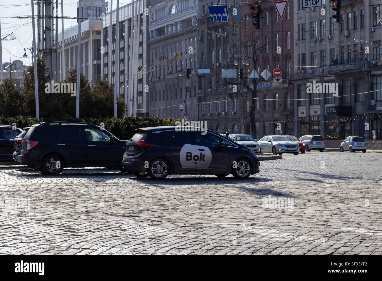 Kiev, Ukraine – 15 mars 2026 : Une voiture Bolt attend sur une place pavée dans une zone métropolitaine, illustrant une infrastructure de transport à la demande moderne au milieu Banque D'Images