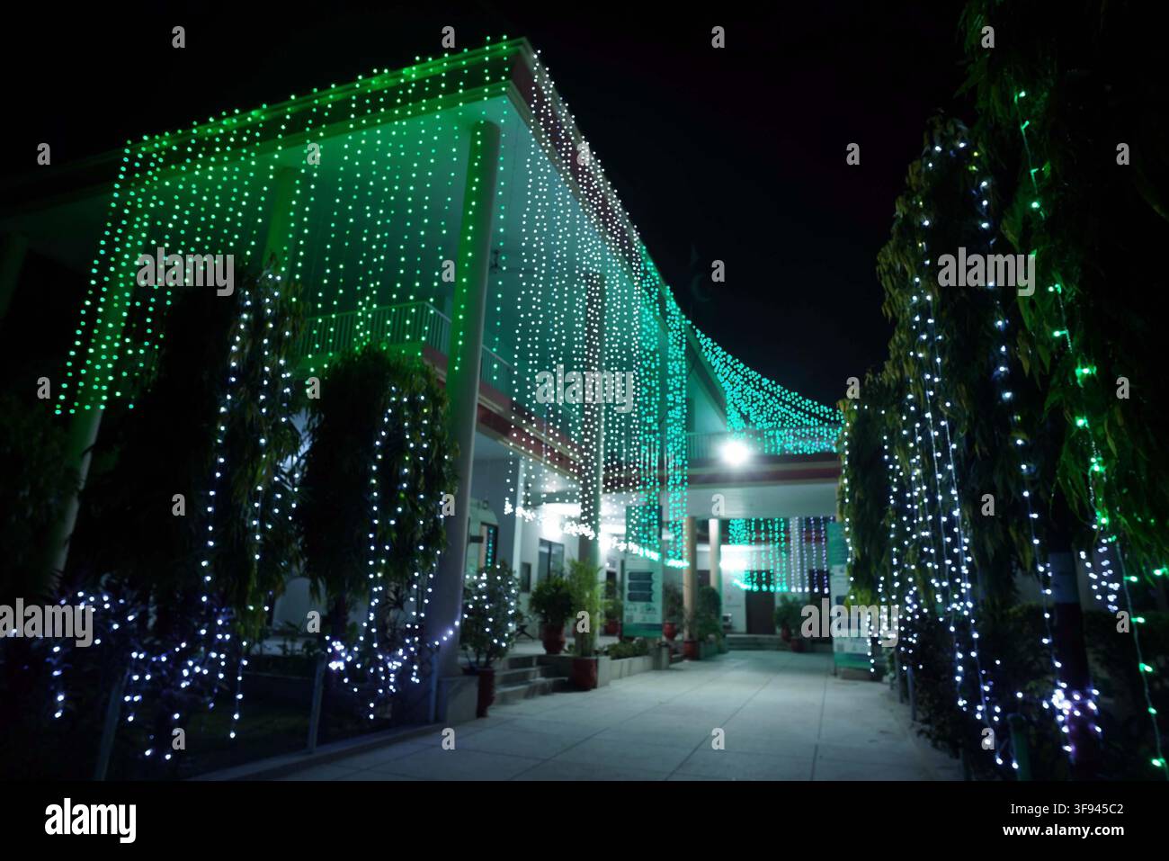 GUJRANWALA, PAKISTAN - 14 août 2026 : À l'occasion du 79e jour de l'indépendance du Pakistan, le bâtiment du conseil de district de Gujranwala était décoré de lumières vertes vives et de lumières blanches fraîches, créant un spectacle lumineux contre le ciel nocturne. L'événement, qui a eu lieu le vendredi 14 août 2026, était marqué par une atmosphère festive avec les colonnes blanches proéminentes du bâtiment et la végétation environnante décorées de guirlandes lumineuses. Cette célébration met en lumière l'esprit durable et les traditions culturelles de la nation, caractérisées par des décorations symboliques comprenant un motif de croissant de lune et d'étoile. De tels spectacles soulignent l'importance de Banque D'Images
