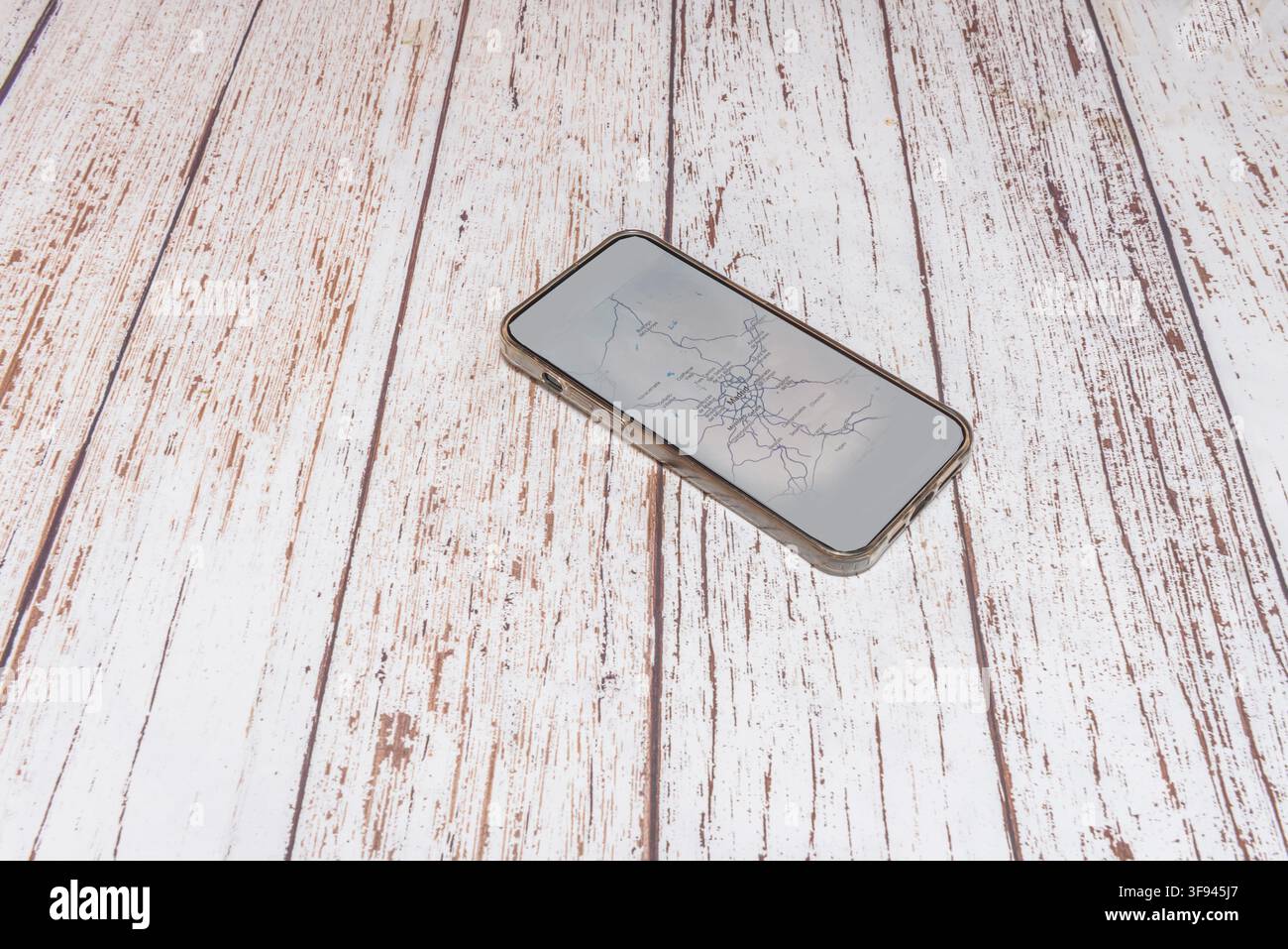 Smartphone affichant une carte de Madrid à l'écran, reposant sur une table en bois blanc défraîchi Banque D'Images