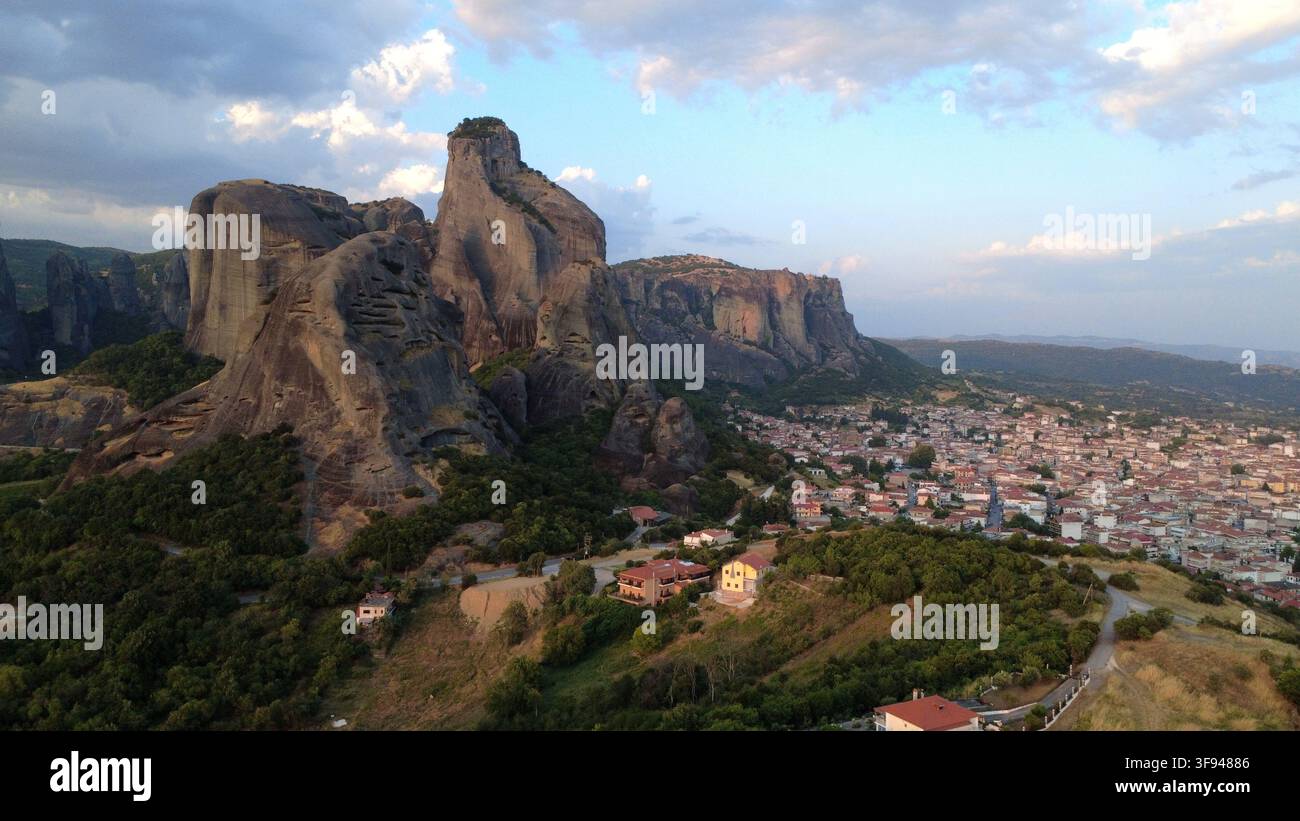 Vue aérienne des impressionnants piliers rocheux des Météores dominant la ville de Kalambaka à l'heure dorée, avec des forêts luxuriantes et un paysage urbain étendu Banque D'Images
