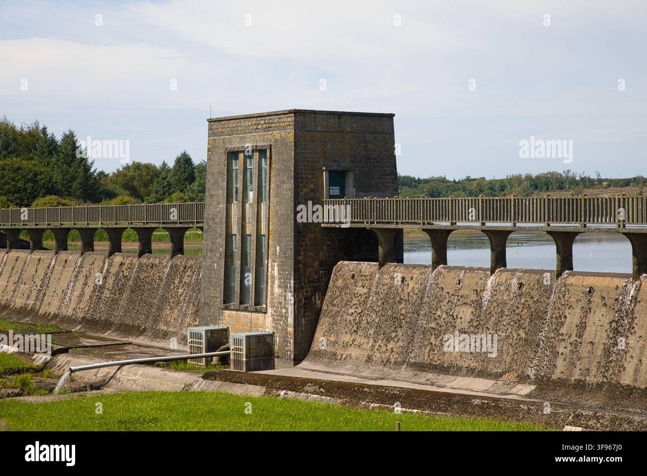La tour de contrôle en pierre et le mur de barrage en béton au réservoir de Llyn Cefni près de Llangefni, île d’Anglesey, Pays de Galles. Banque D'Images