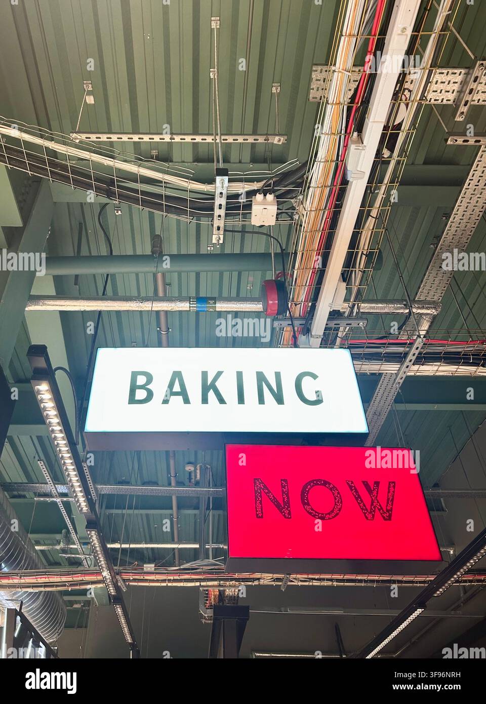 Ensemble de lumières illuminées Baking Now dans un plafond industriel avec câblage apparent Banque D'Images