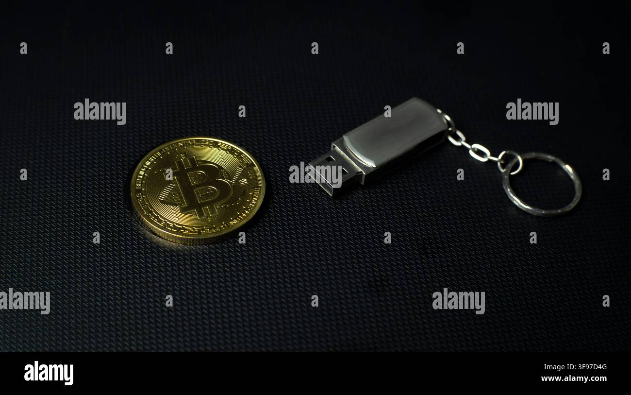 Pièce Bitcoin à côté d’une clé USB sur une surface sombre, représentant un portefeuille crypto, un stockage numérique, une sauvegarde, la sécurité et la confidentialité Banque D'Images
