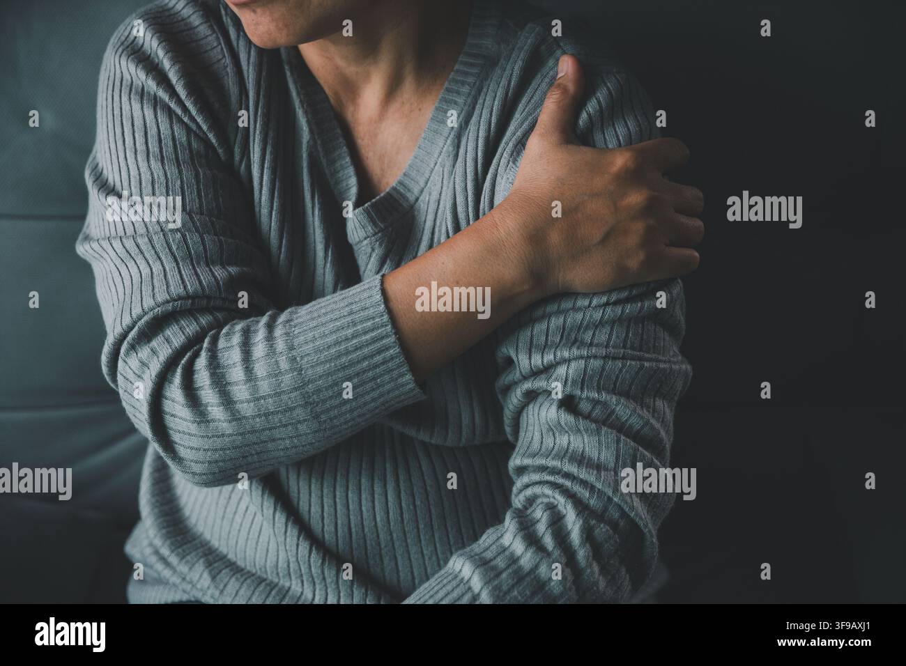 gros plan d'une femme adulte tenant son épaule douloureuse tout en étant assise à la maison, représentant une tension musculaire, une douleur articulaire, une raideur, une blessure et une charge physique Banque D'Images