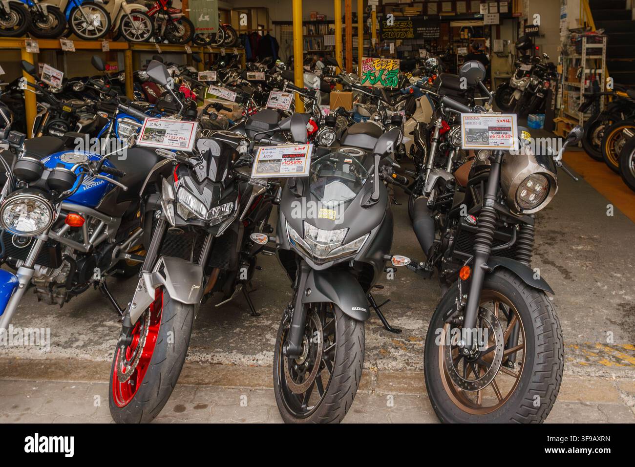 Des rangées de motos et scooters d'occasion avec étiquettes de prix garés devant un concessionnaire de motos dans la ville d'Osaka. Banque D'Images