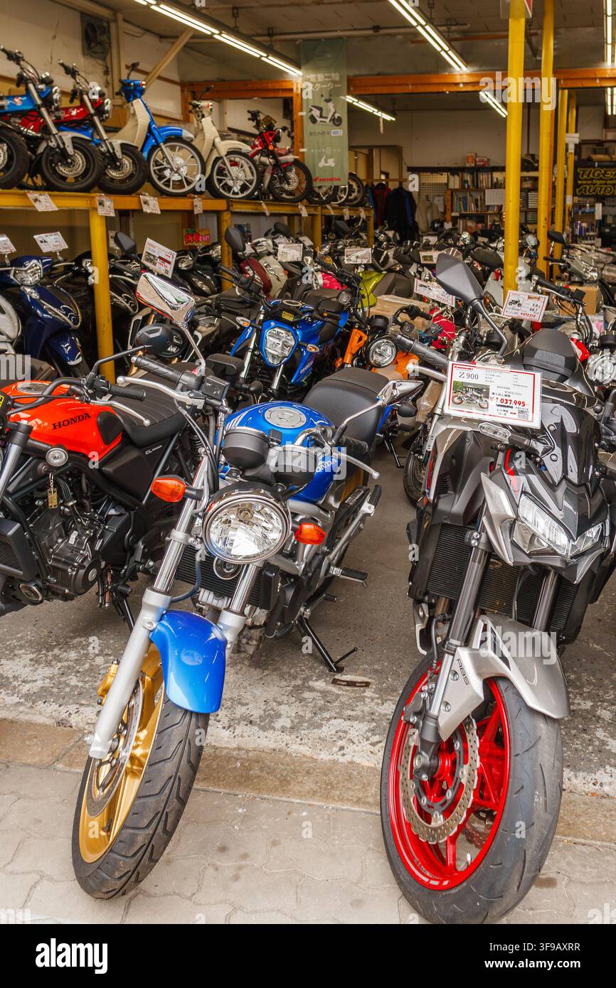 Vue intérieure d'un showroom de concessionnaire de motos d'occasion avec des rangées de motos exposées et des étagères avec des mopeds dans la ville d'Osaka. Banque D'Images