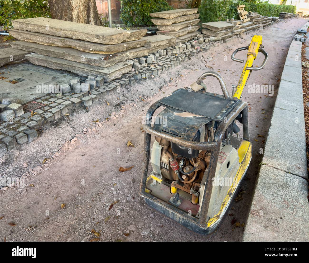 Compacteur de plaques sur un chantier de construction de chemin urbain – Travaux routiers, compactage du sol et développement des infrastructures Banque D'Images