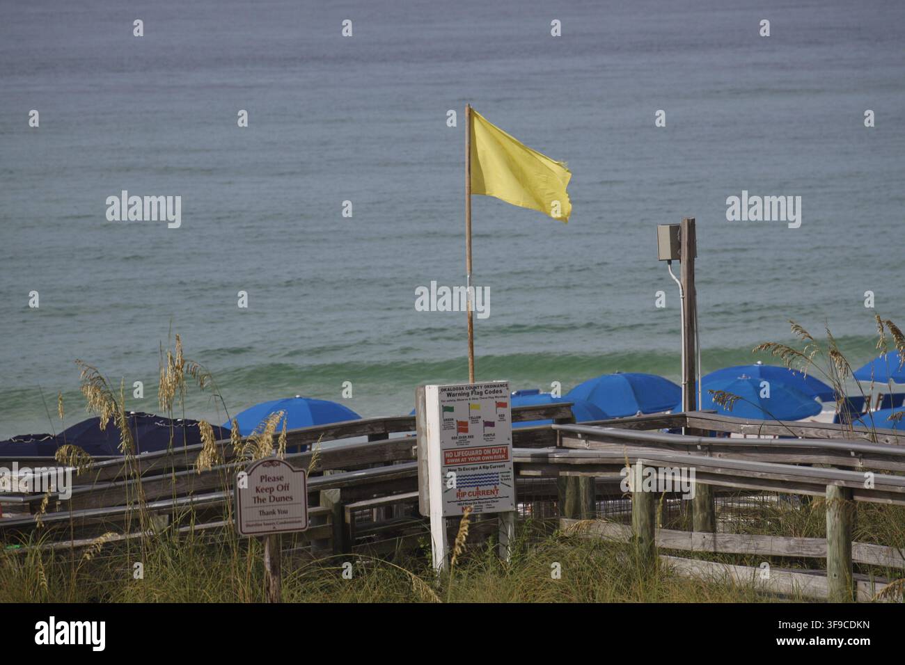 Drapeau de sécurité jaune sur la plage de sable de Destin, en Floride, avec le golfe du Mexique calme sous un ciel gris bas et couvert. Banque D'Images