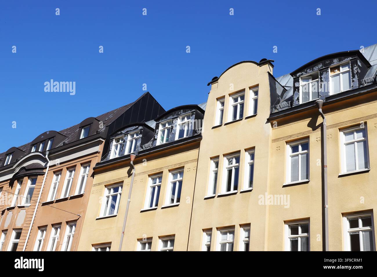 Bâtiments résidentiels historiques colorés avec des façades décoratives, de grandes fenêtres et des toits mansardés distinctifs en Suède sous un ciel bleu clair. Banque D'Images