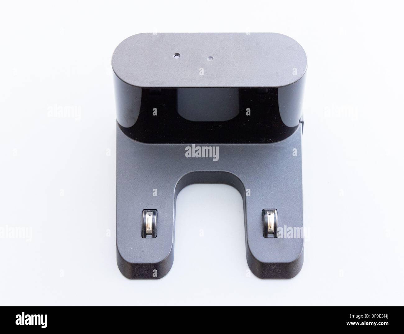Une base de charge pour robot aspirateur gris foncé repose sur un fond blanc Banque D'Images