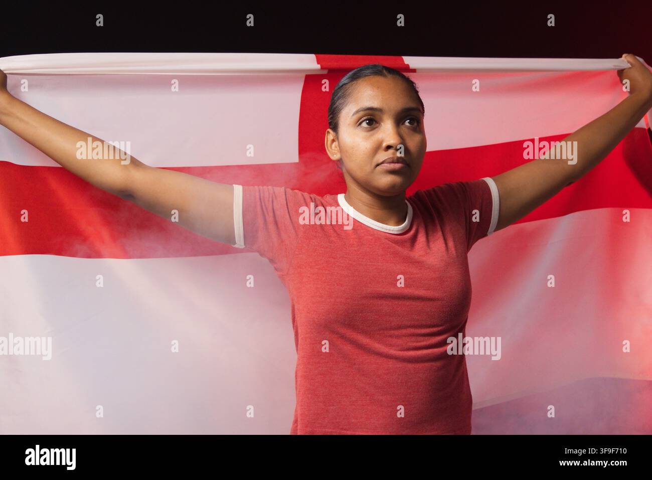 Femme debout dans un studio les bras tendus tenant un drapeau blanc avec une croix rouge en T-shirt rouge Banque D'Images
