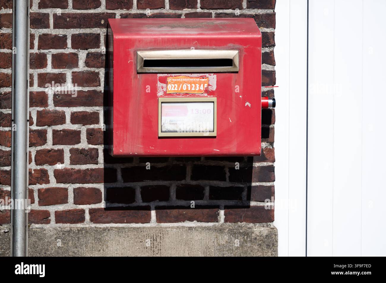 Une boîte postale rouge traditionnelle de bpost à Sint-Maria-Oudenhove, Zottegem, Flandre orientale. La boîte postale belge familière se dresse dans la rue du village. Sint-M Banque D'Images