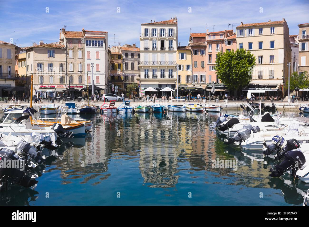 Des bateaux à moteur amarrés dans le port de La Ciotat, entourés de maisons historiques colorées et de restaurants en bord de mer en France. Banque D'Images