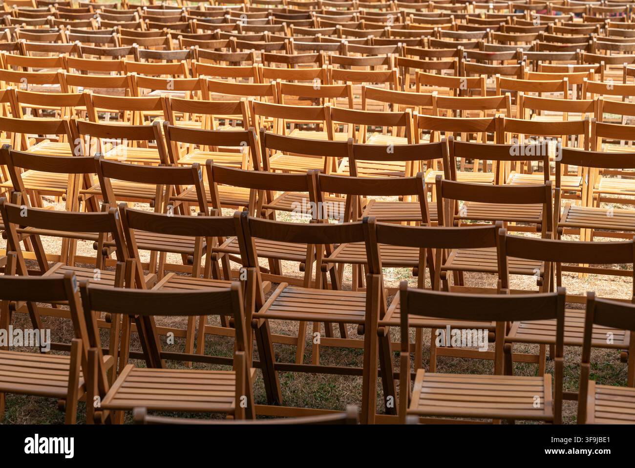 Configuration professionnelle de lieu d'événement avec de nombreuses chaises en bois dans un champ ouvert Banque D'Images