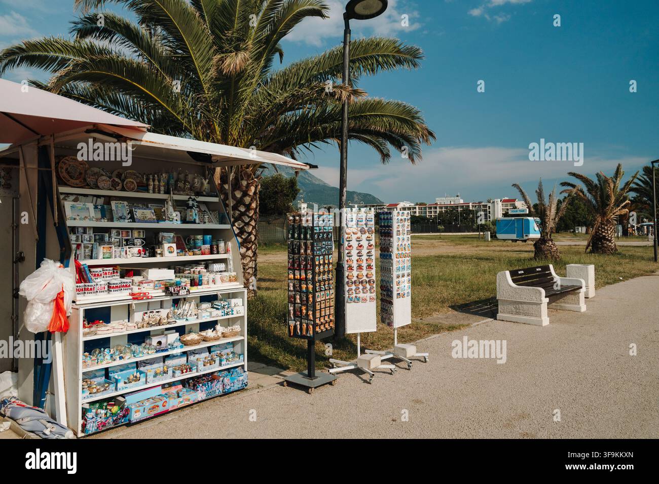 Bar, Monténégro – 26 juin 2026. Kiosque à souvenirs au bord de la mer exposant des aimants, des tasses et des cadeaux à côté de palmiers sur une promenade côtière. Banque D'Images