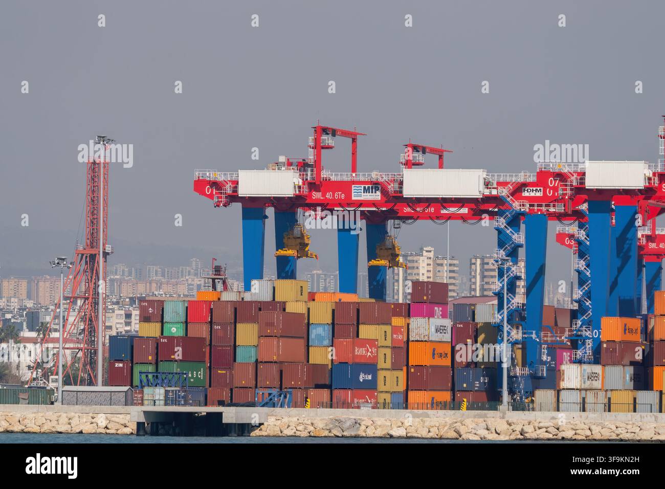 Mersin, Turquie - 22 février 2026 : Grues portiques rouges et bleues organisant des conteneurs d'expédition empilés colorés au port international de Mersin (MIP), wit Banque D'Images