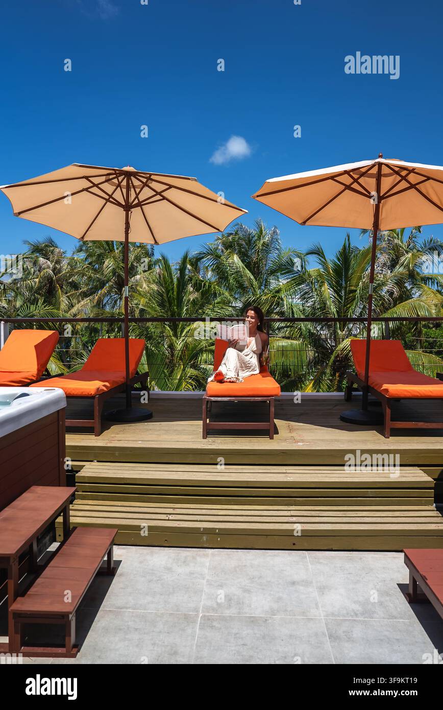 Femme lisant un livre sur une chaise longue aux Maldives Banque D'Images