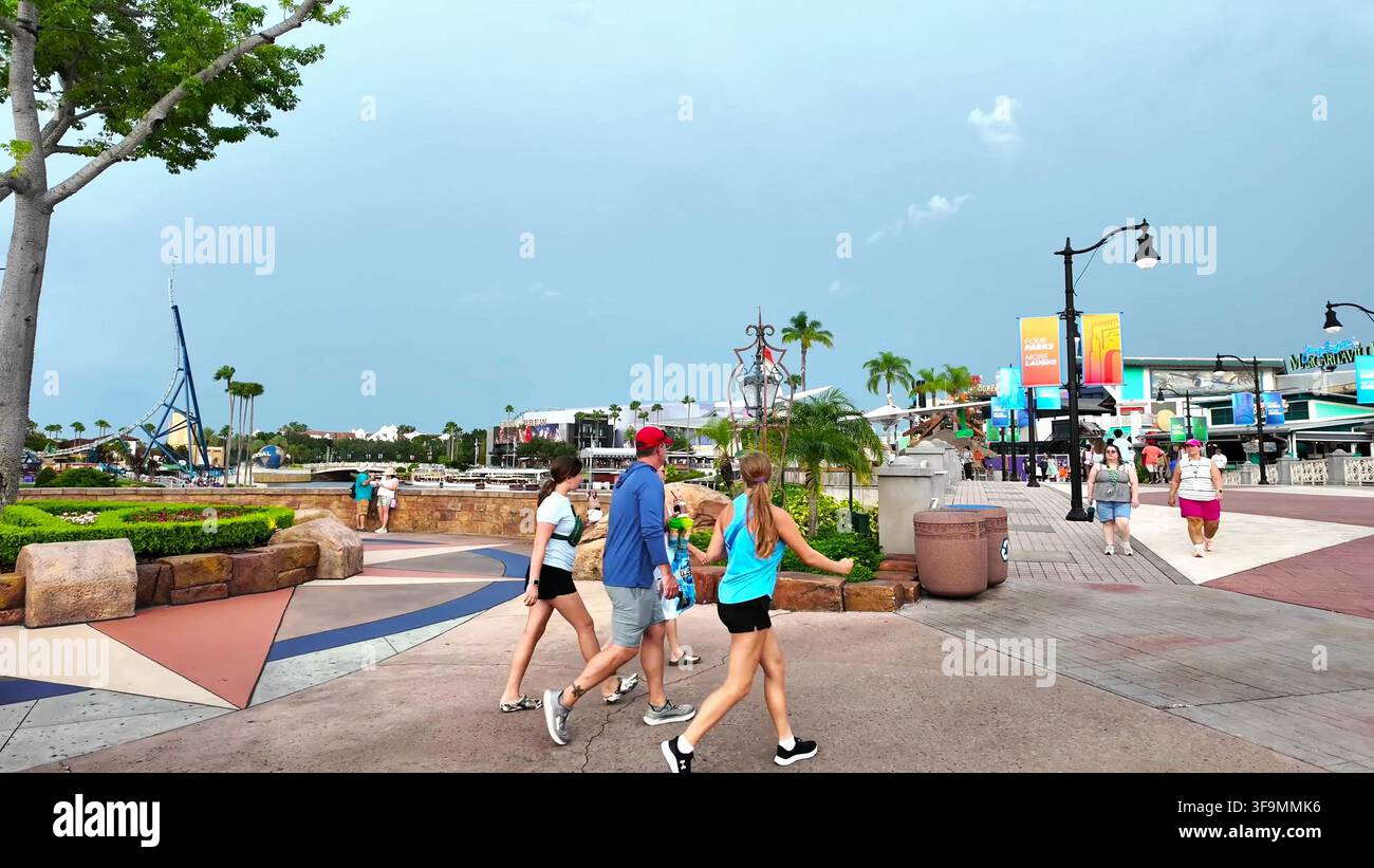 ORLANDO, FL, ÉTATS-UNIS - 16 AOÛT 2026 : Touristes non identifiables marchant sur un chemin pavé dans un grand parc d'attractions en plein jour. Banque D'Images