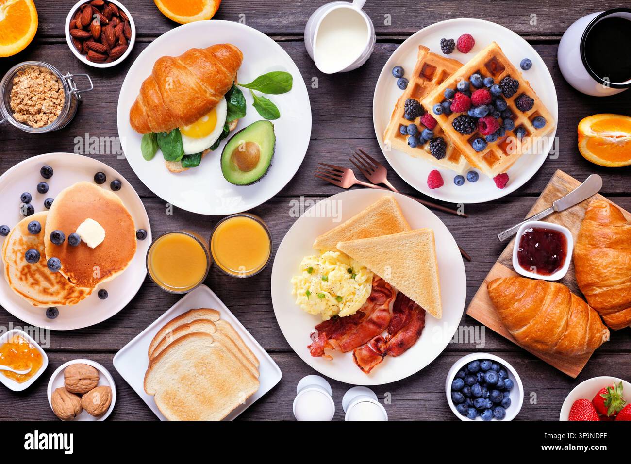Scène de table pour petit-déjeuner ou brunch sur un fond en bois sombre. Vue aérienne. Variété d'aliments sucrés et salés. Banque D'Images