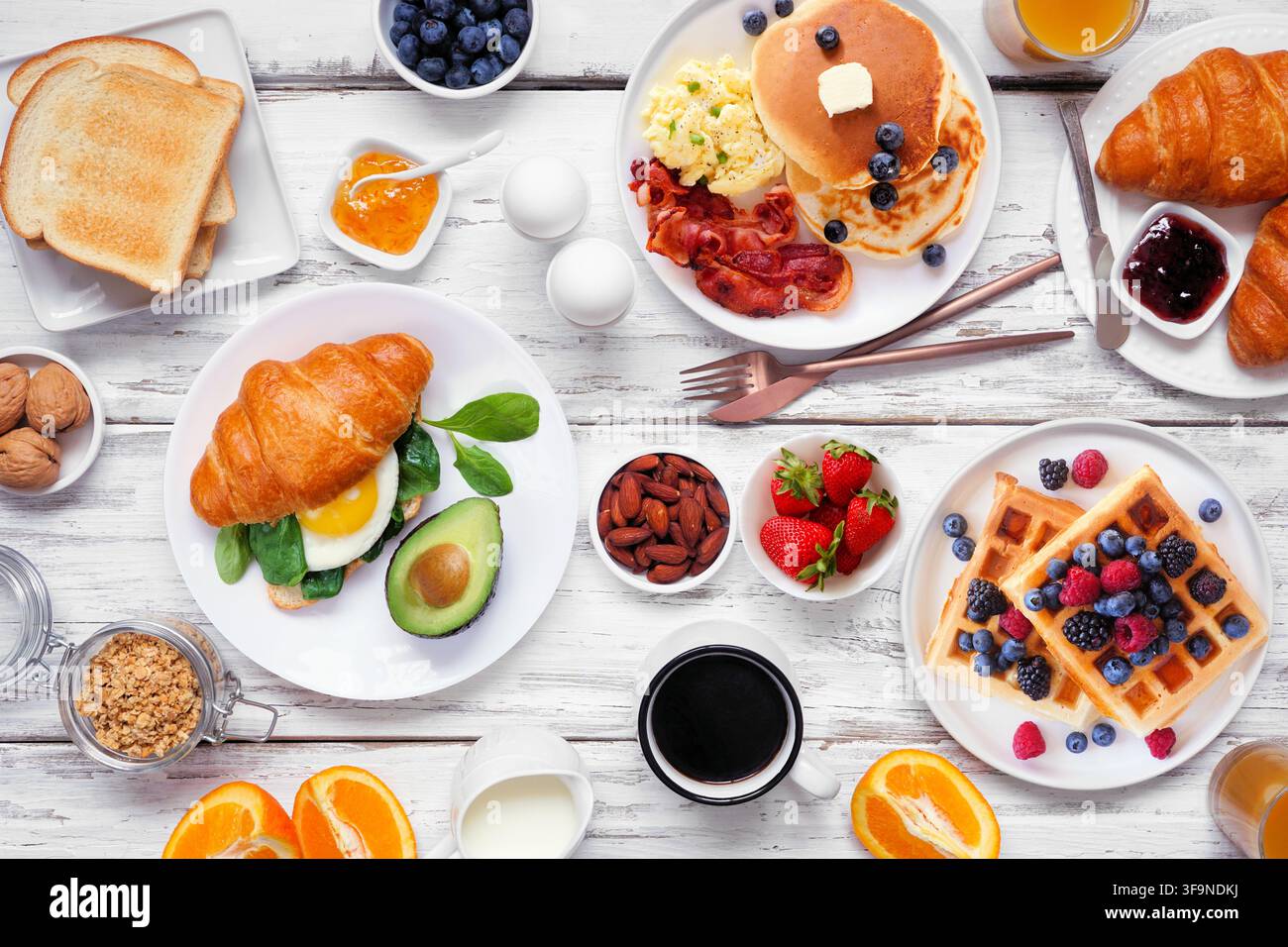 Scène de table pour petit-déjeuner ou brunch sur un fond en bois blanc. Vue de dessus. Sélection d'aliments sucrés et salés. Banque D'Images