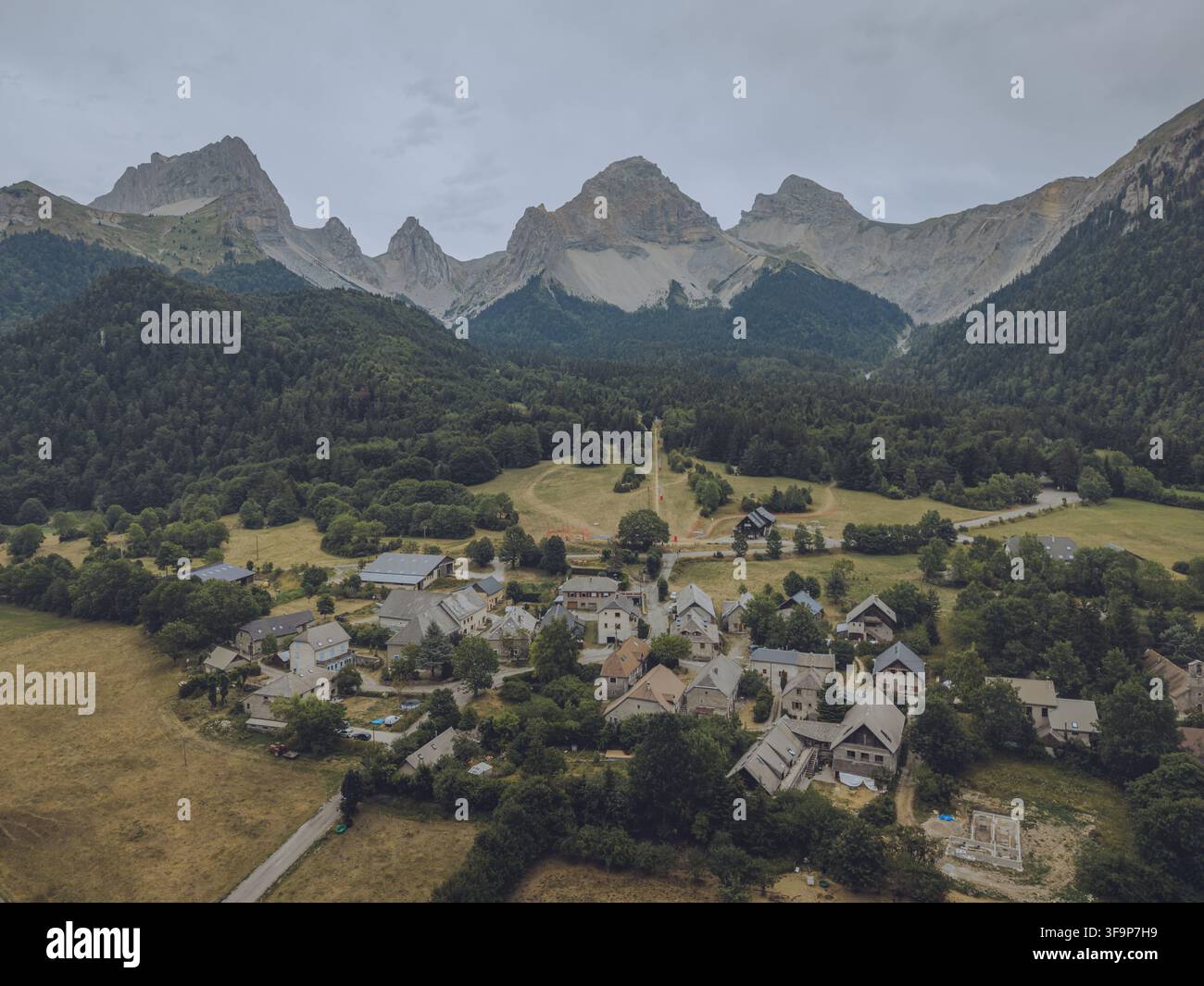 Vue aérienne du Vallon de la Jarjatte avec des maisons en pierre nichées dans la vallée entourée de forêts denses et de pics montagneux dramatiques à Lus-la-Croix Banque D'Images