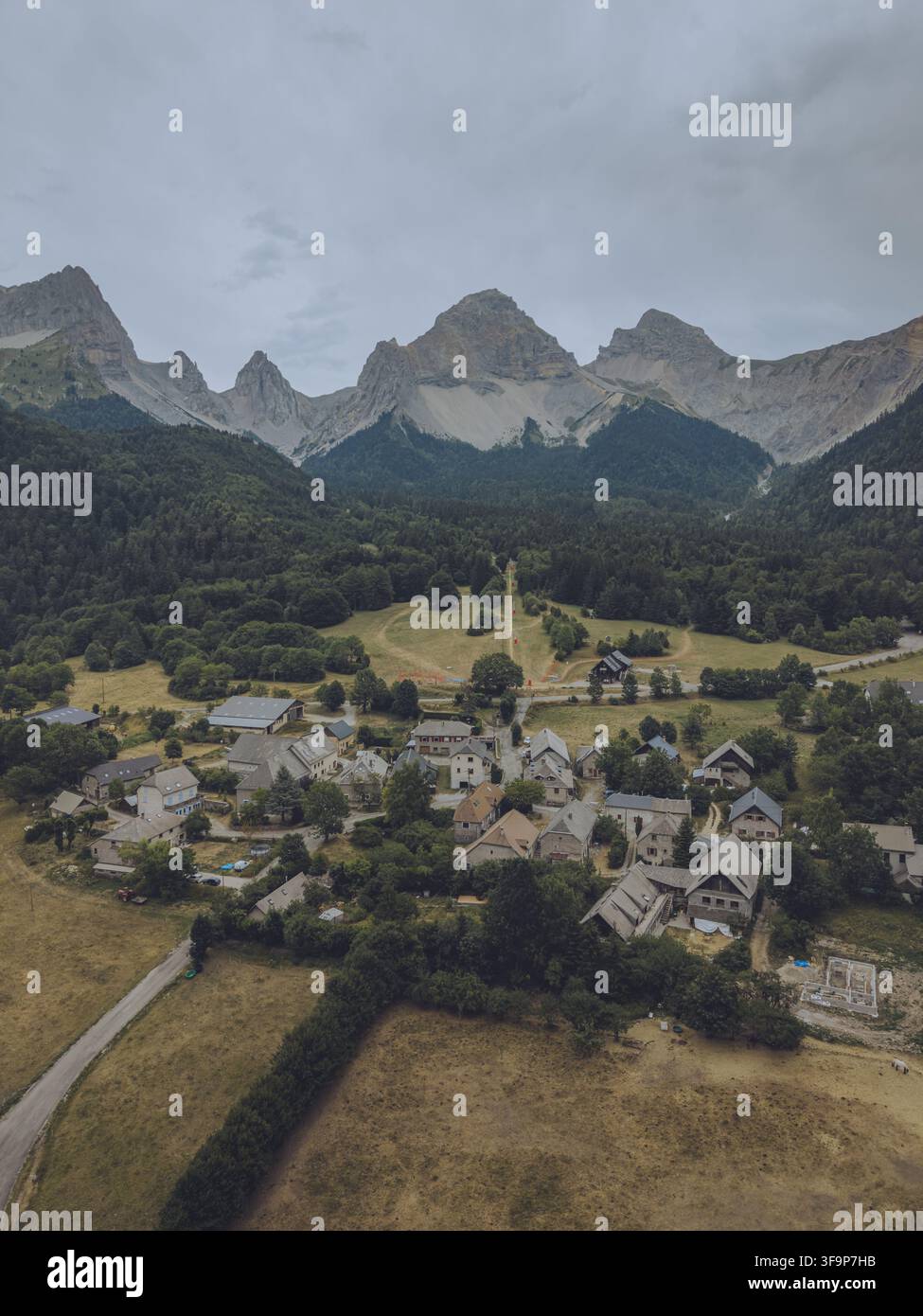 Vue aérienne du Vallon de la Jarjatte avec son petit village niché parmi des forêts luxuriantes et des sommets montagneux dramatiques sous un ciel nuageux à Lus-la- Banque D'Images