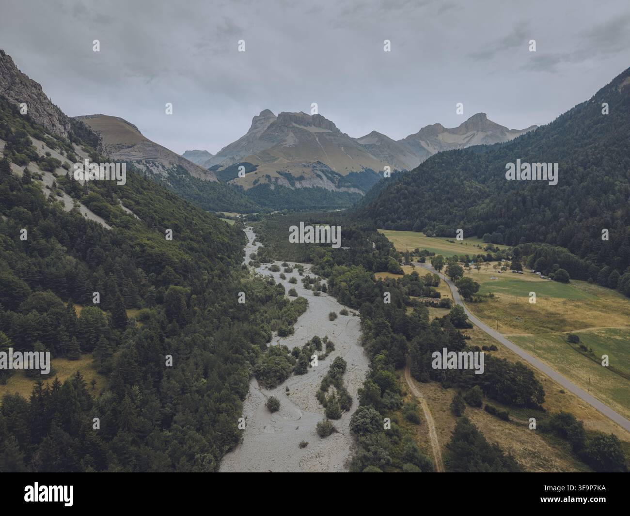 Vue aérienne du Vallon de la Jarjatte présentant un lit de rivière sinueux, des forêts luxuriantes et des sommets montagneux environnants sous un ciel nuageux à Lus-la-Cro Banque D'Images