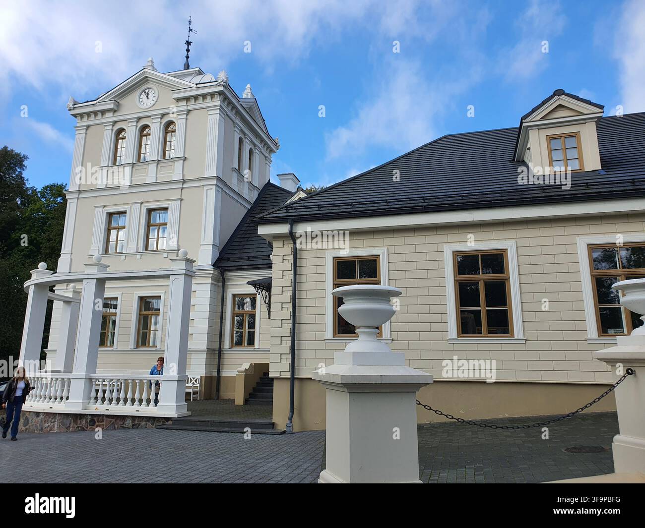 Un manoir néoclassique historique avec des revêtements en bois couleur crème et des ornements architecturaux blancs. Le bâtiment possède une tour d'horloge proéminente avec Banque D'Images